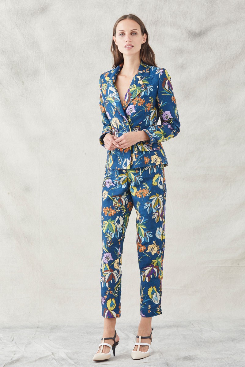 comprar online traje dos piezas de chaqueta americana y pantalon pitillo con ollados en los laterales y cordones de antelina malva en tejido jacquard con fondo azul oscuro y un precioso estampado de flores en tonos malvas, blancos, amarillos, naranja